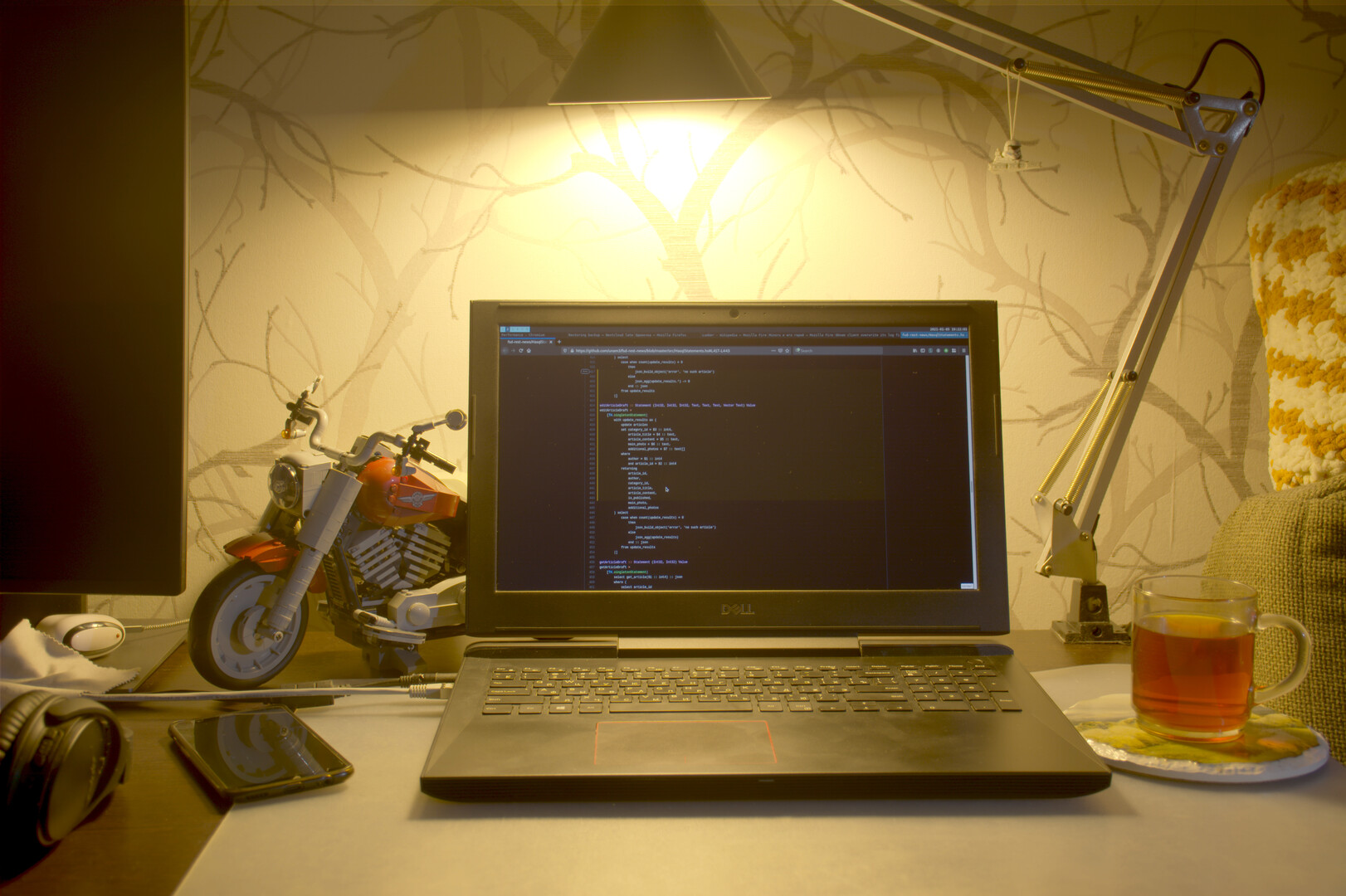 Рабочее место с ноутбуком, телефоном, чашкой чая и LEGO-моделью
    мотоцикла